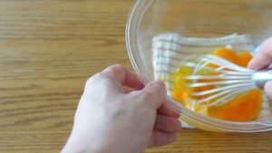 別のボウルに卵を割り入れ、泡立てないようボウルの底に泡立て器をつけたままぐるぐる混ぜる。砂糖とはちみつを加え、溶けてツヤが出るまで混ぜる